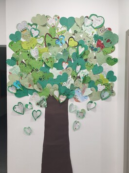 Poster of a tree with green hearts as leaves. Each heart is a tree planted by the school