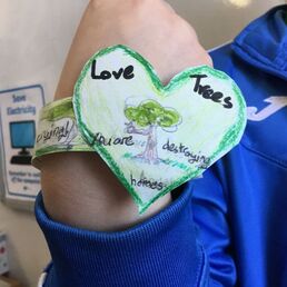 Picture of a child wearing a heart bracelet he made with the words 