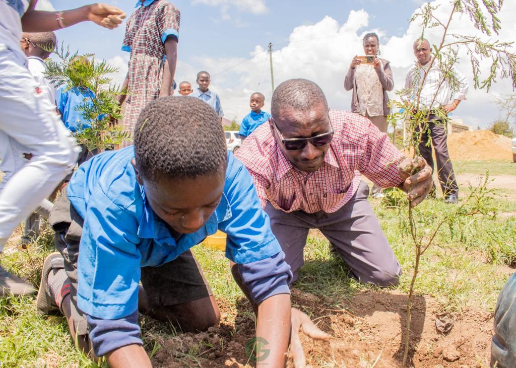 A teaching showing his pupil how to plant a tree