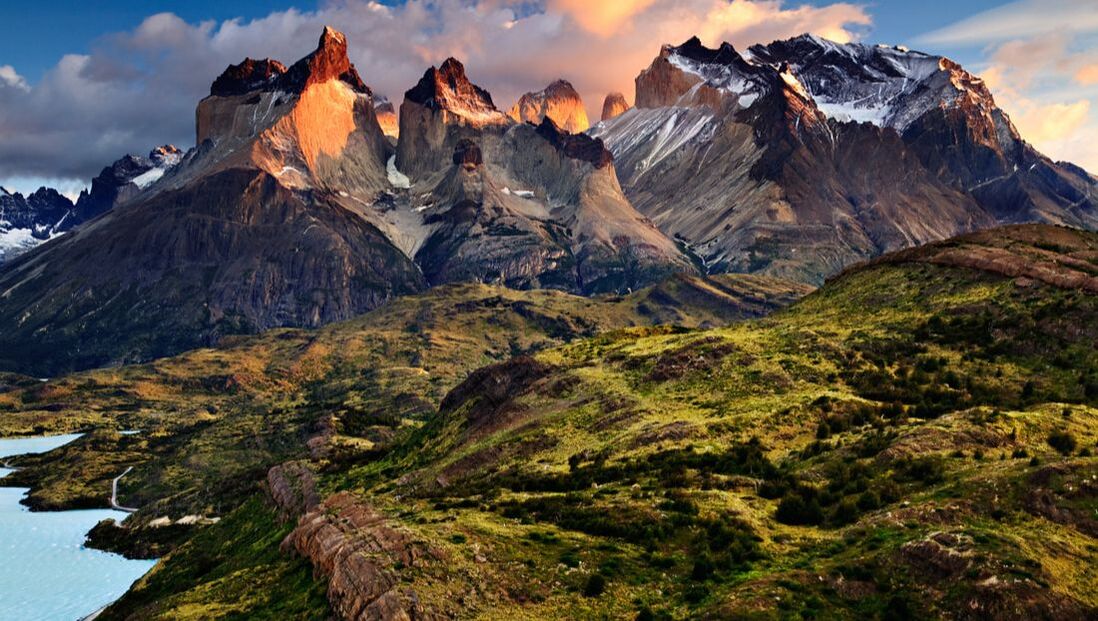 Picture of snow capped mountains in the Andes with a green landscape beneath 