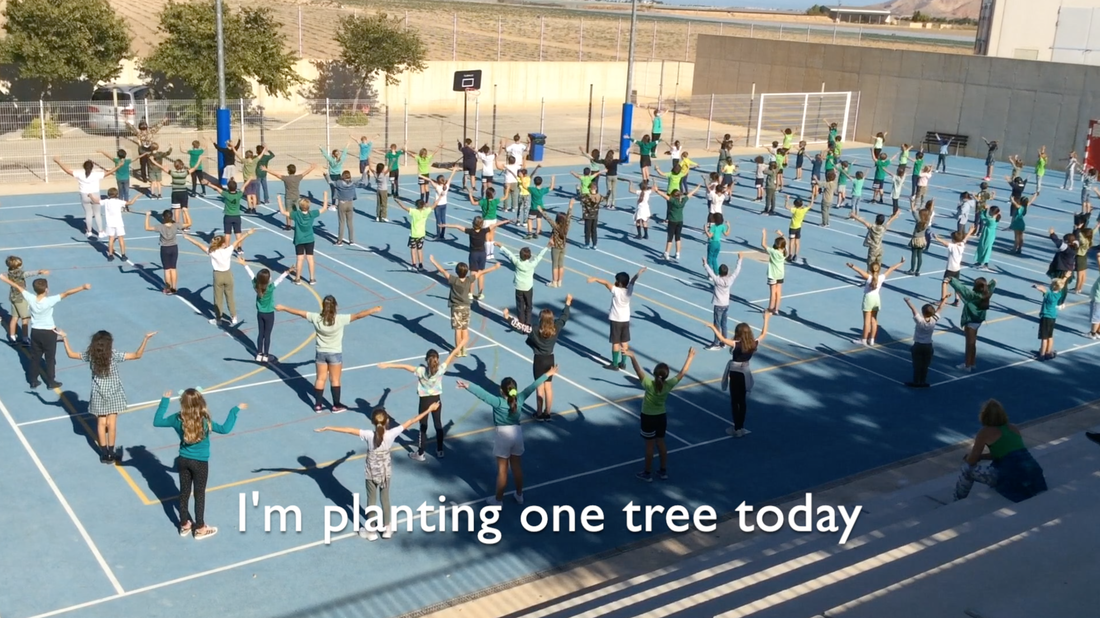 Picture of Spanish kids in the playground, dressed in Green dancing to a song. The caption reads 